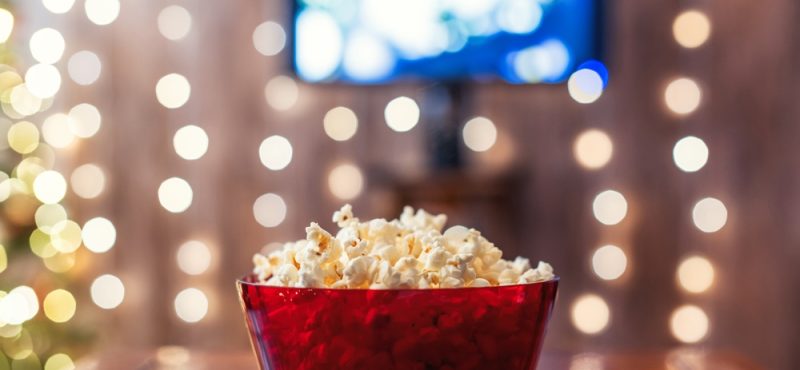 Red bowl with popcorn on the table. Home cinema. Tv.