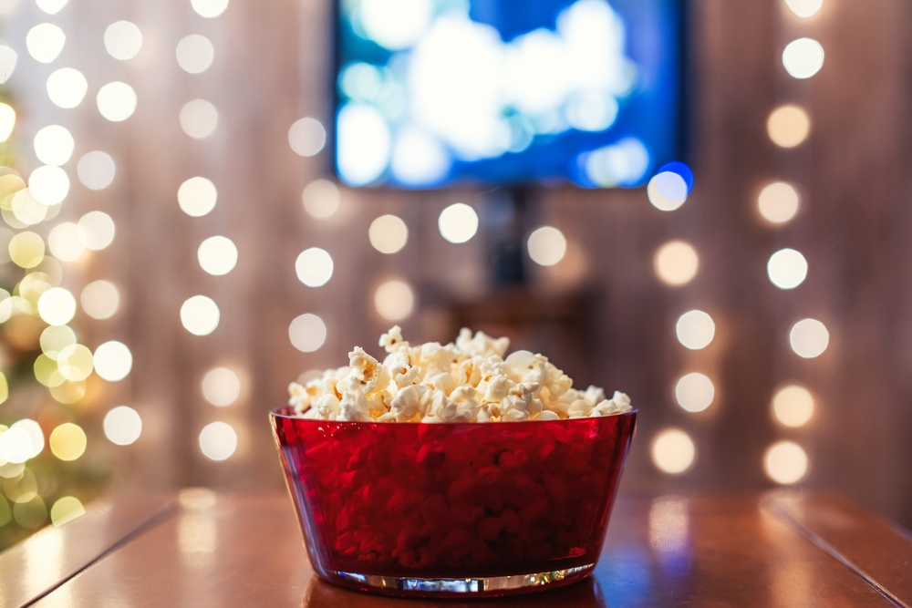 Red bowl with popcorn on the table. Home cinema. Tv.