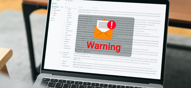 Hand using laptop with shows a warning screen of new email notifications, hack password and personal data. Concept of cyber crime